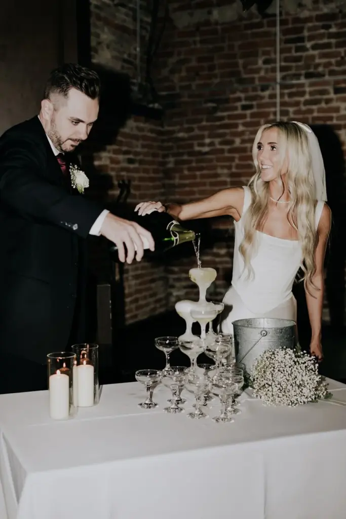Couple pouring a champagne tower at their wedding reception