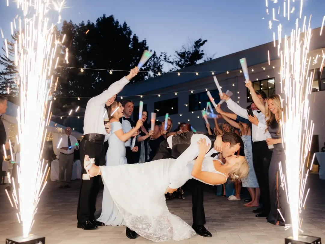Couple sharing a dip kiss framed by cold spark fountains at a Detroit wedding send-off