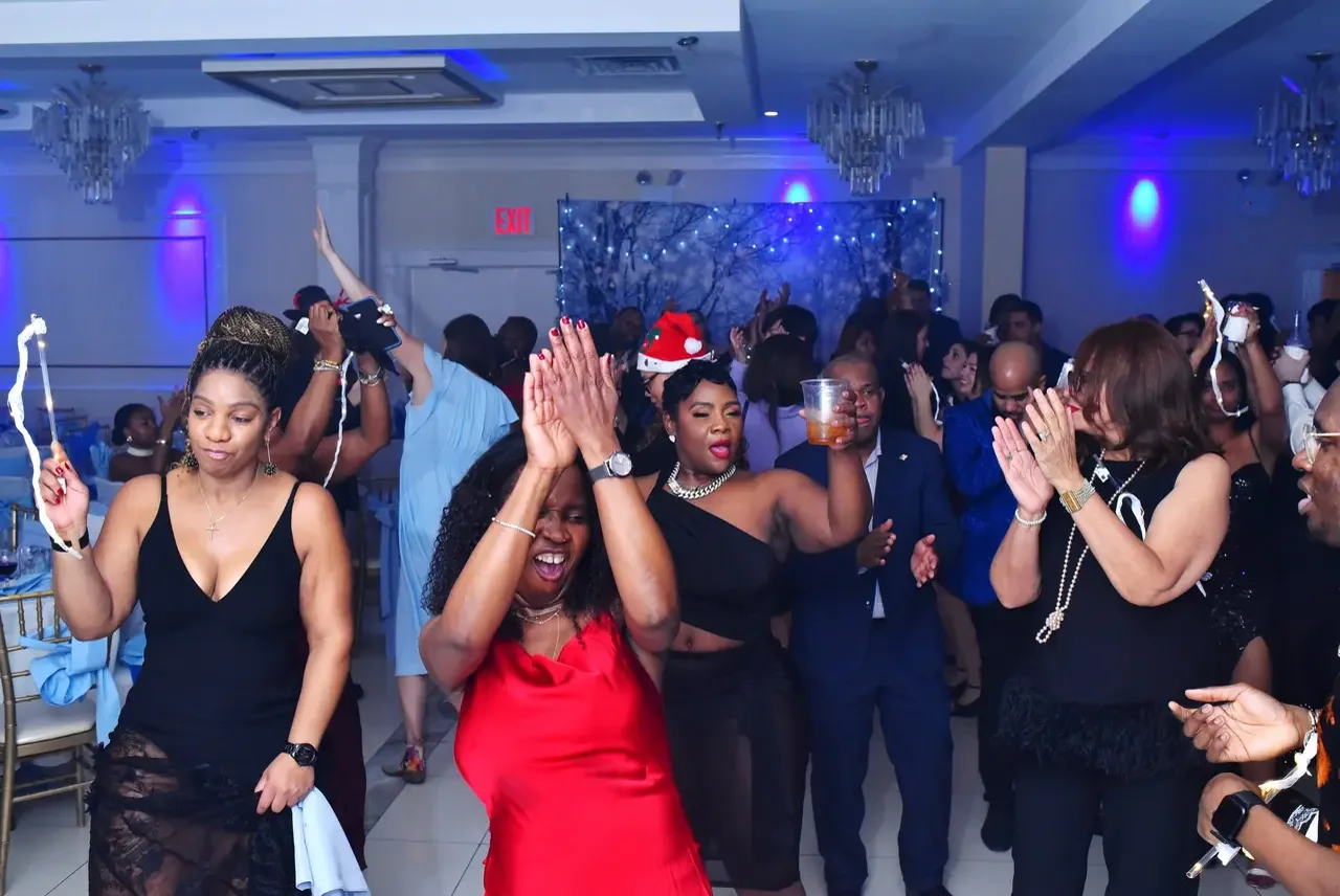 Guests packing the dance floor at a lively corporate holiday party with blue uplighting