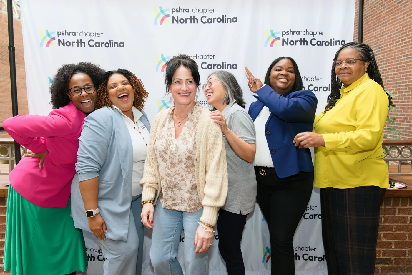 Group of colleagues laughing together at a corporate event photo backdrop
