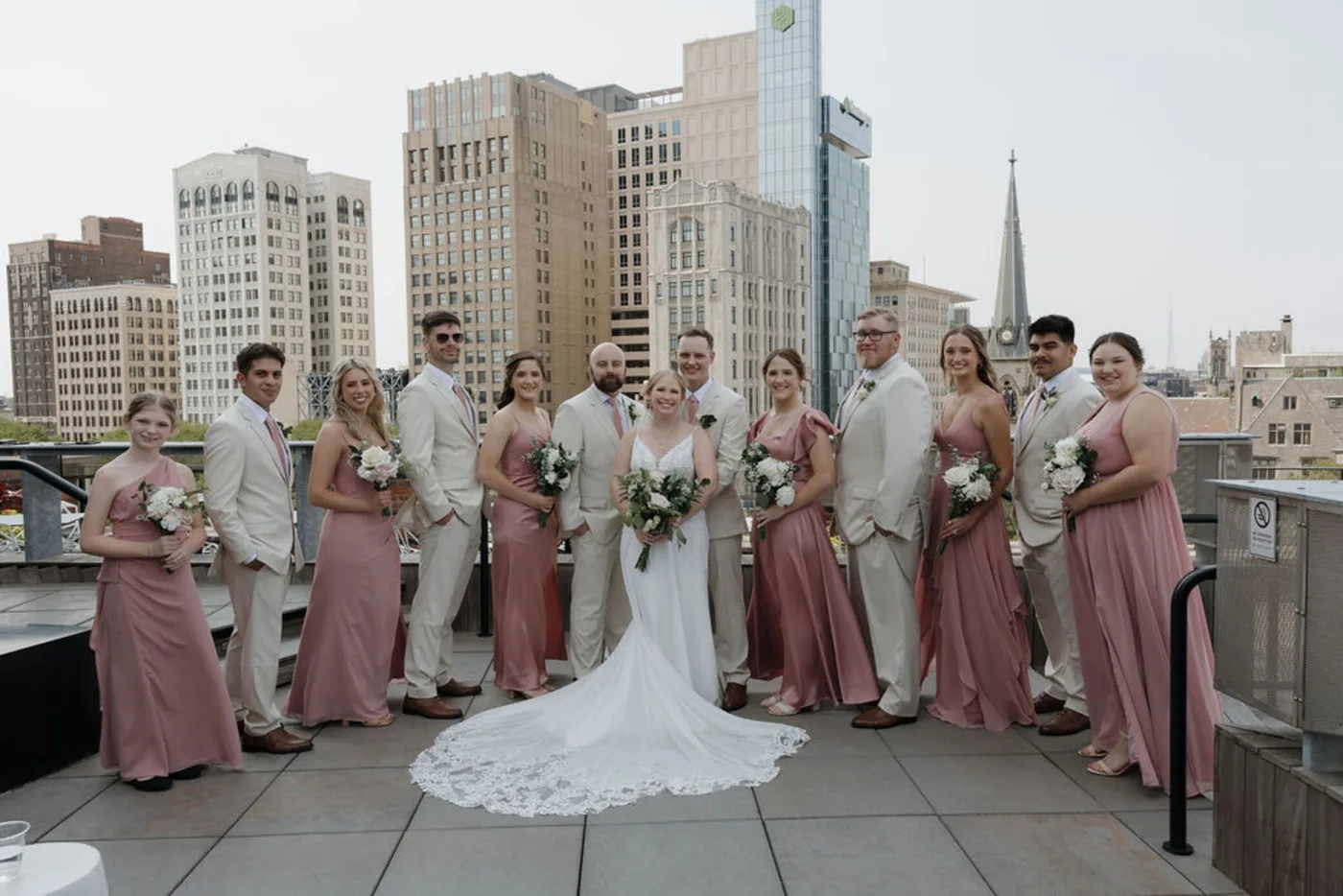 Bridal party posing for a Detroit riverfront wedding with the downtown skyline behind them