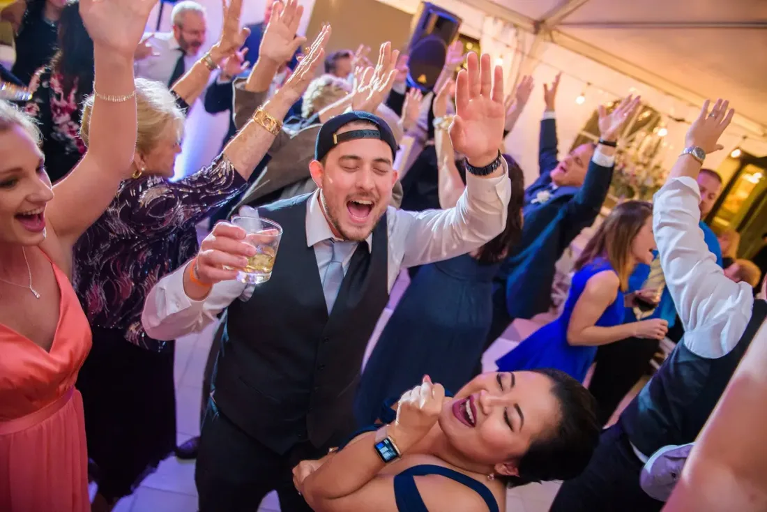 Wedding guests cheering with drinks raised on the dance floor