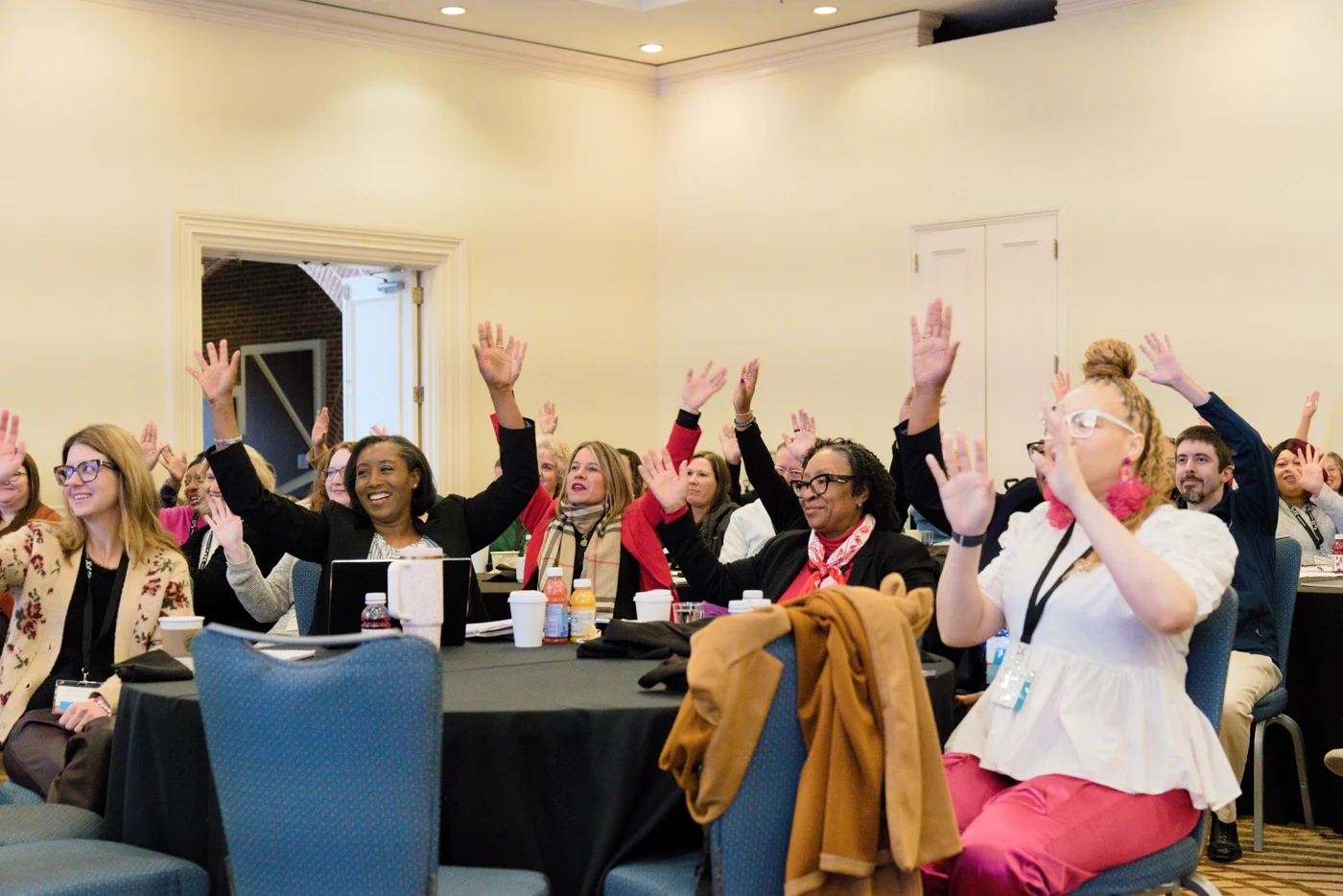 Conference attendees with hands raised