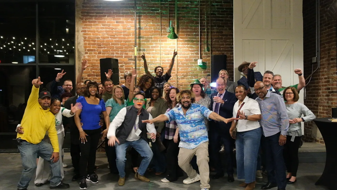 A large group of guests posing and celebrating together at a corporate event with SKAN the DJ