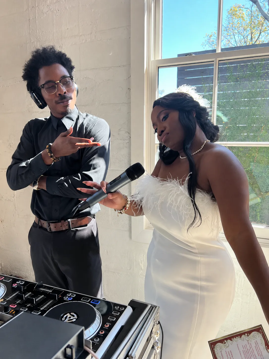 Tevin at the DJ controller with a bride holding the microphone at her wedding